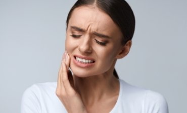 Woman wincing from a toothache - Emergency Dentistry at Meadows Dental Group