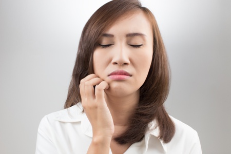 woman with facial pain touching her jaw