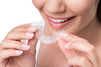 Woman holding Invisalign aligner 